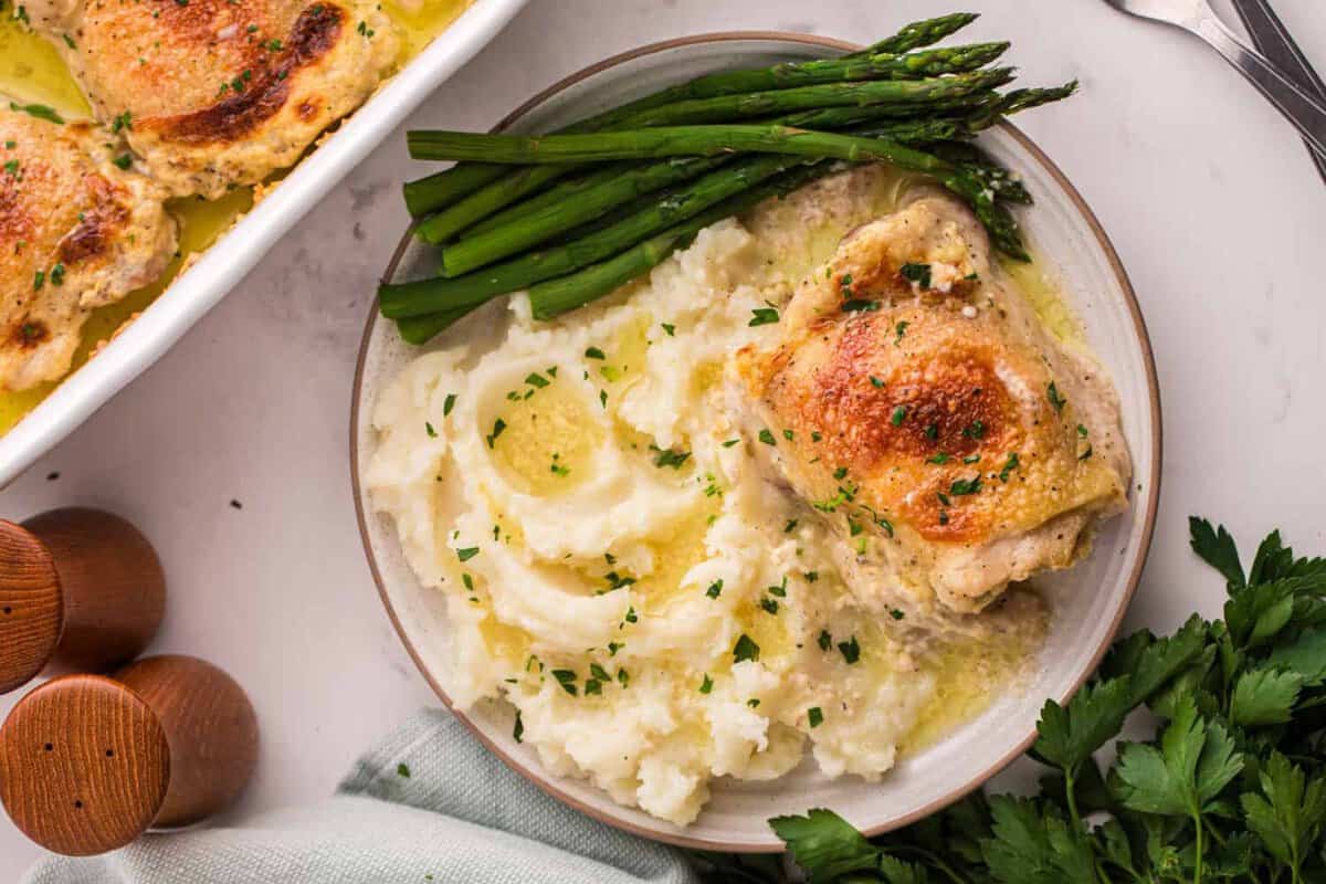 A serving of amish chicken with buttery mashed potatoes and asparagus.
