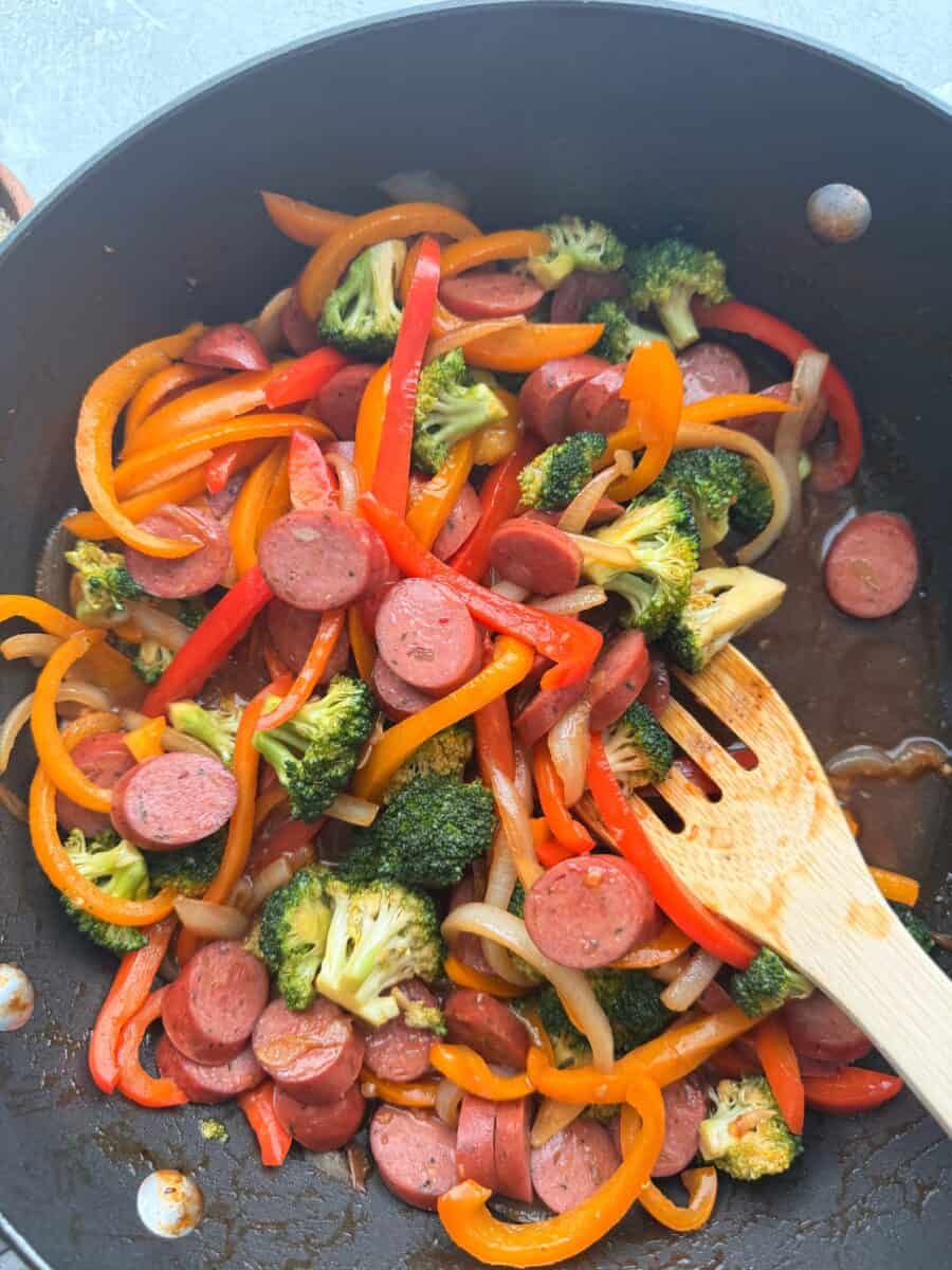 Cooking sausage stir fry in a skillet.