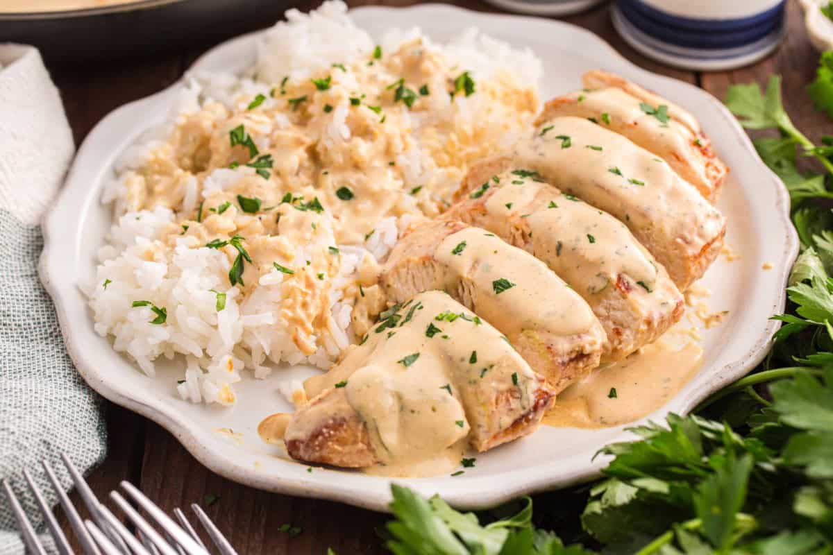 Sliced cream cheese chicken breasts served on a plate with rice.