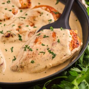 Cream cheese chicken breast being lifted out of a skillet with a spatula.