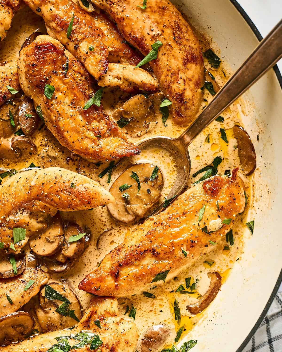 Chicken tenders in a skillet with a creamy tarragon sauce with mushrooms.