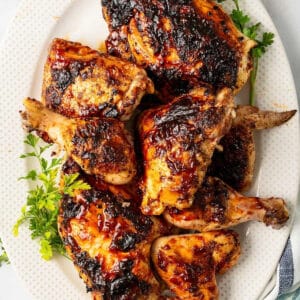 A plate of grilled whole BBQ chicken cut into pieces.