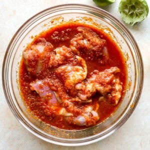 Chicken thighs being marinated in a bowl.