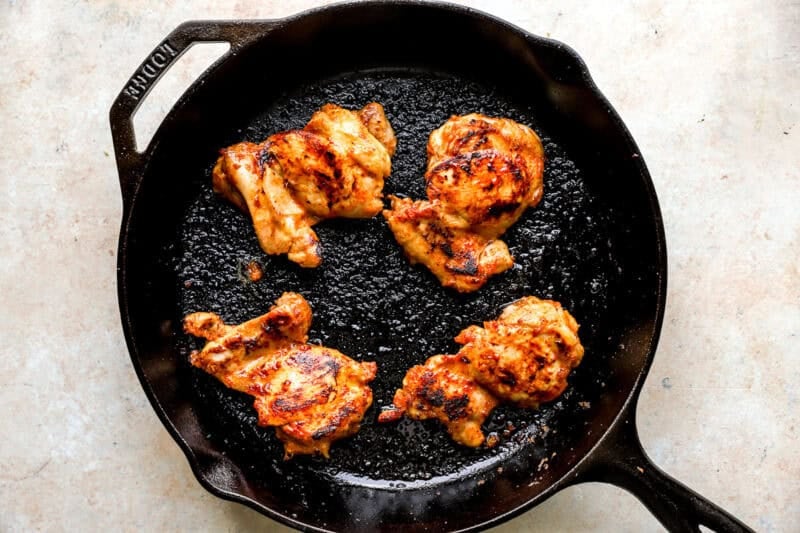 Chicken being cooked in a skillet.