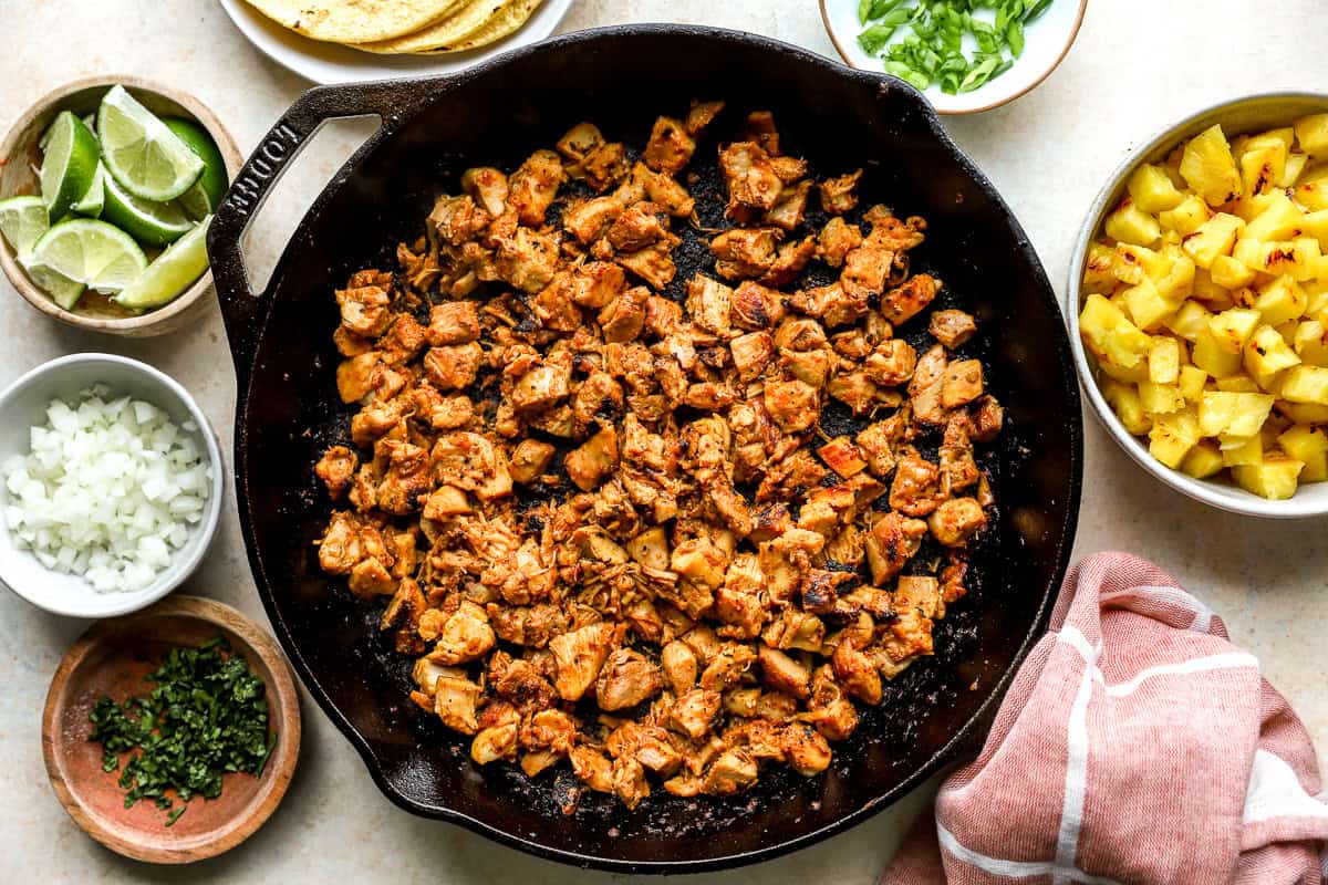 Bite-sized pieces of chicken cooking in al pastor sauce.
