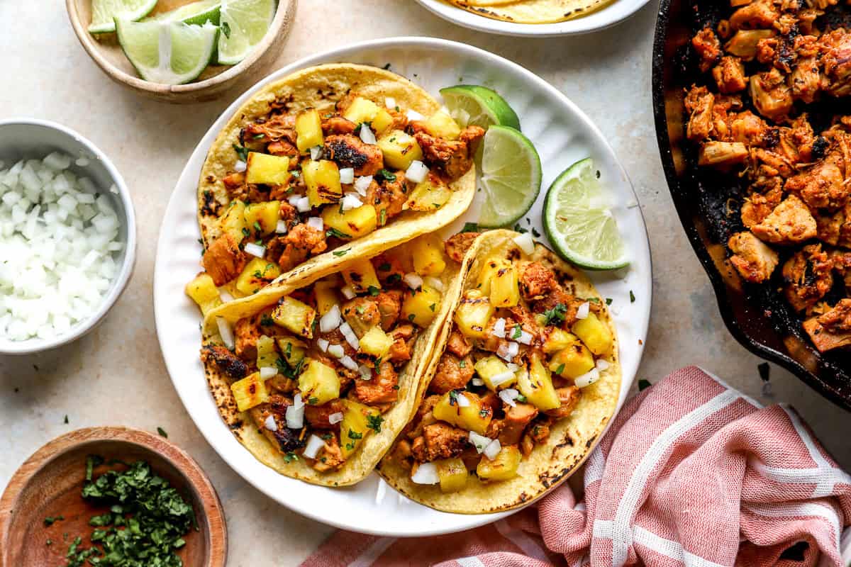 Chicken al pastor tacos served with pineapple and lime.