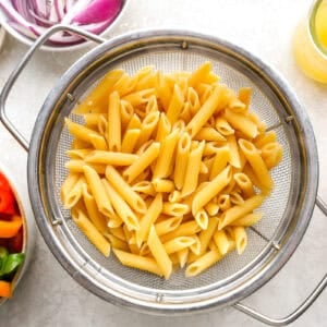 Cooked pasta in a sieve.