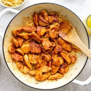 Chicken pieces being browned in a skillet.
