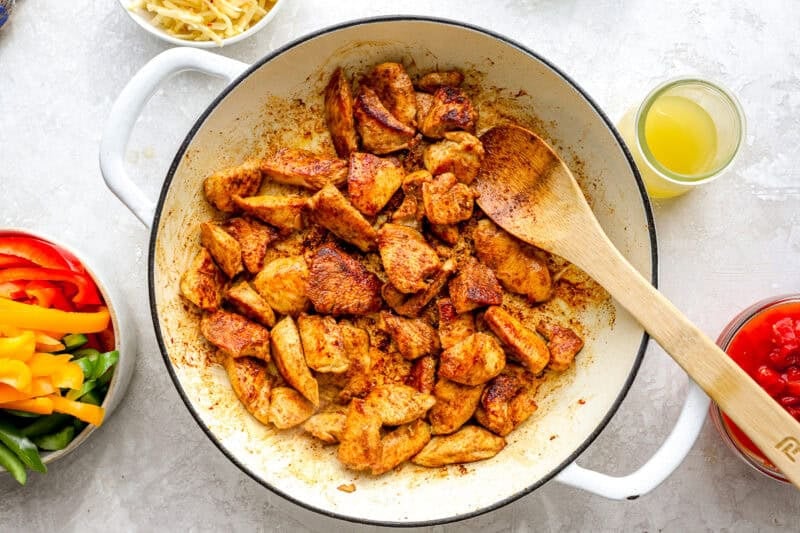 Chicken pieces being browned in a skillet.