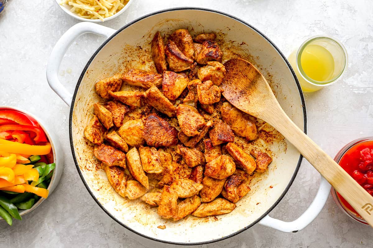 Chicken pieces being browned in a skillet.