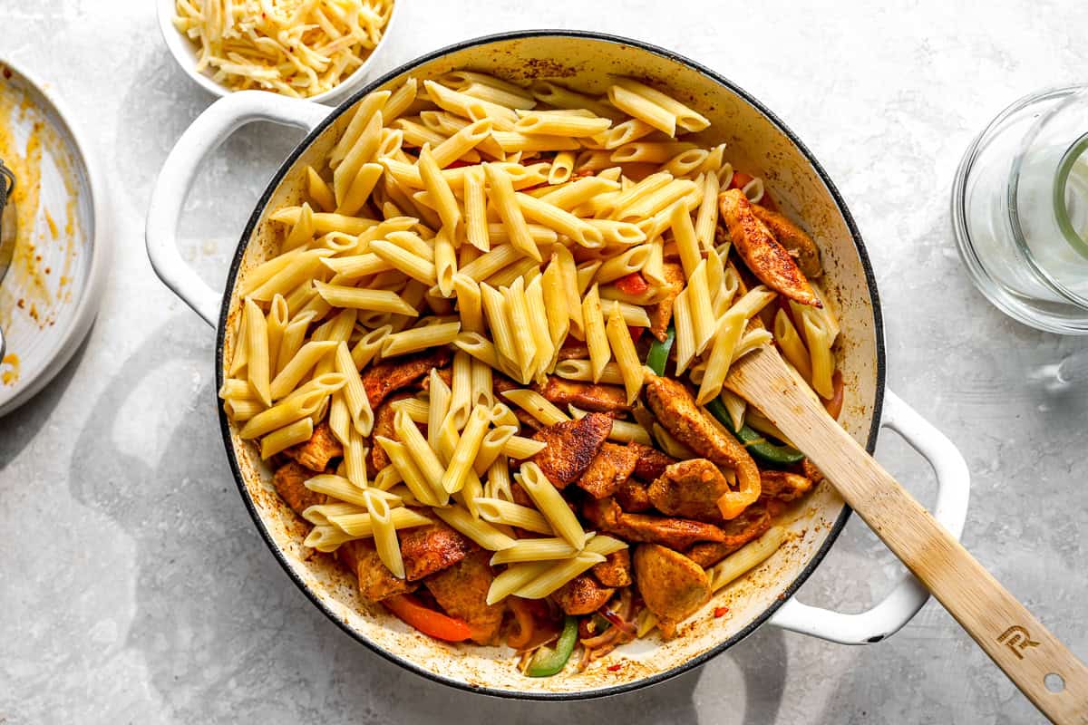 Stirring pasta and chicken into fajita pasta.