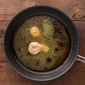 Broth and seasonings added to a skillet.