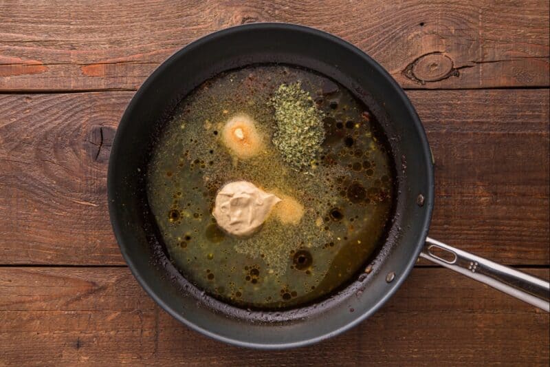 Broth and seasonings added to a skillet.