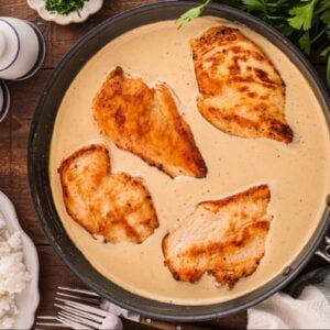 Chicken breasts in crem sauce in a skillet.