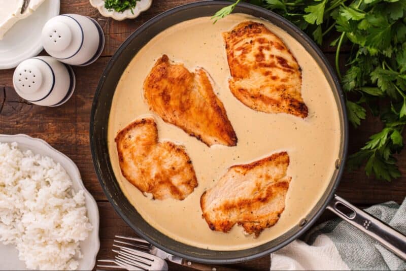 Chicken breasts in crem sauce in a skillet.