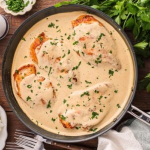 Cream cheese chicken in a skillet garnished with parsley.
