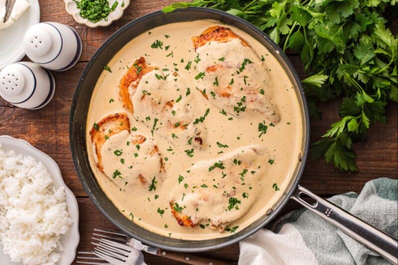 Cream cheese chicken in a skillet garnished with parsley.