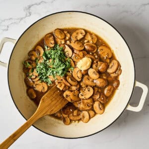 Fresh tarragon added to a pan of mushrooms.