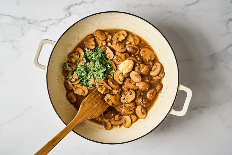 Fresh tarragon added to a pan of mushrooms.