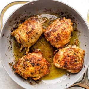 Browned chicken thighs in a skillet.