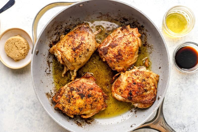 Browned chicken thighs in a skillet.