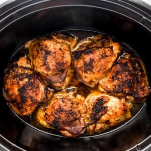 Cooked chicken thighs in a Crockpot.