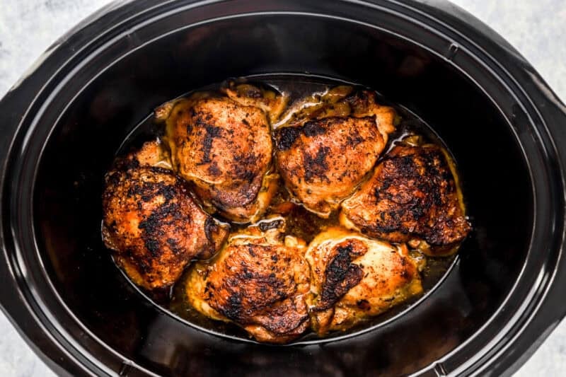 Cooked chicken thighs in a Crockpot.