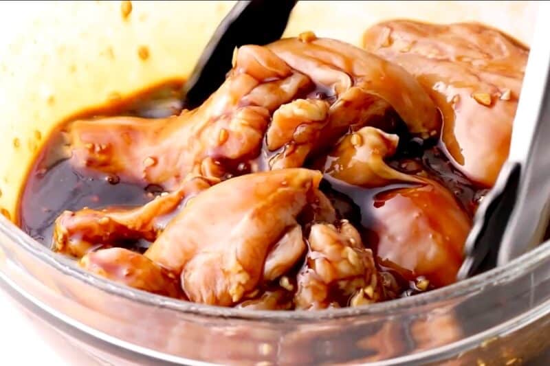 Tossing chicken thighs in huli huli marinade.
