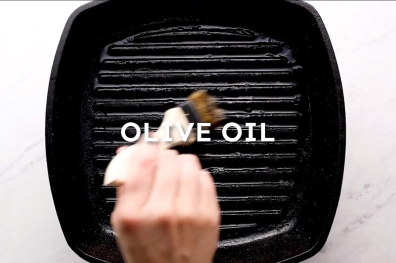 Brushing grill grates with olive oil.