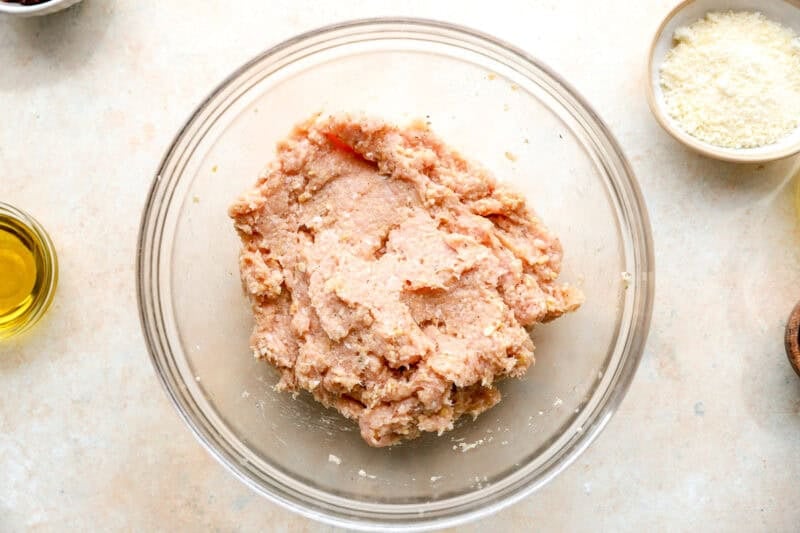 Ingredients for chicken meatballs combined in a bowl.