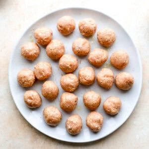 Uncooked meatballs on a plate.