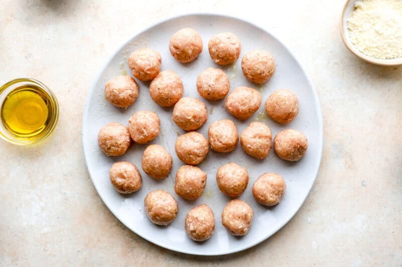 Uncooked meatballs on a plate.