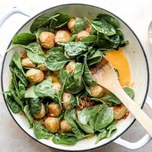 Spinach being stirred into the meatballs.