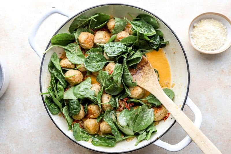 Spinach being stirred into the meatballs.