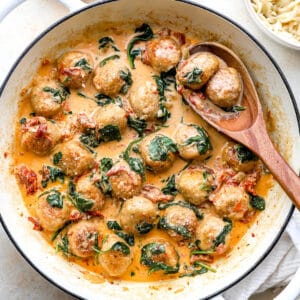 Marry Me Chicken Meatballs in a skillet with a wooden spoon.