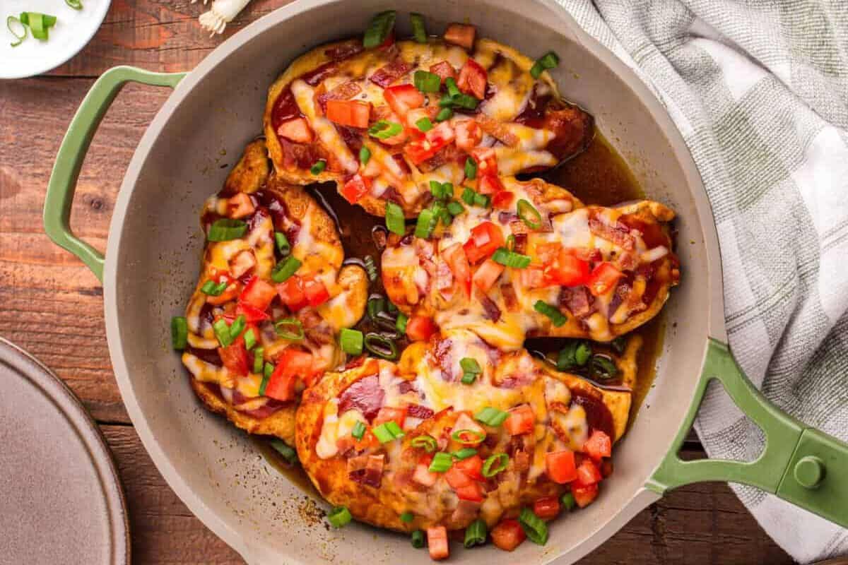 Cooked Monterey chicken garnished with tomatoes and bacon.