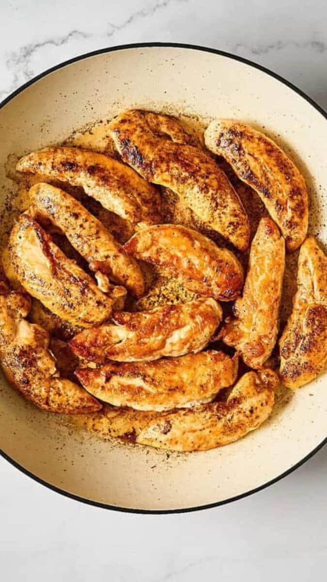 Browned chicken tenders in a pan.