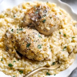 A serving of oven-baked chicken thighs atop a creamy rice mixture.
