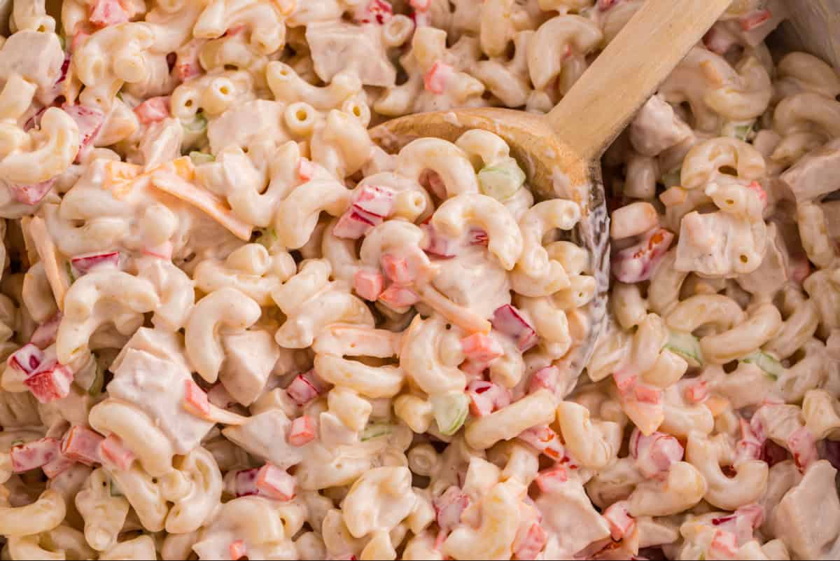 Chicken and macaroni salad with a wooden spoon dipped in.