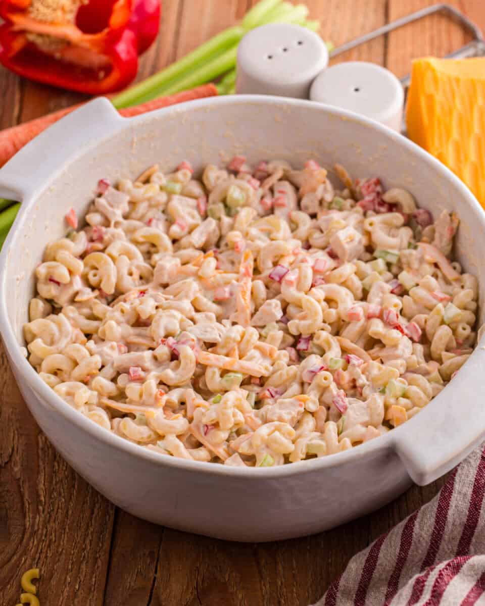 A serving bowl of cold chicken macaroni salad.