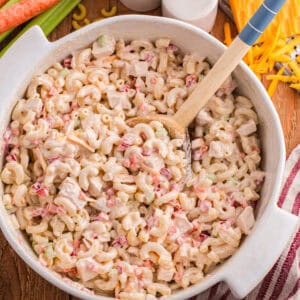 A serving bowl of chilled macaroni salad, filled with nites of chicken and veggies.