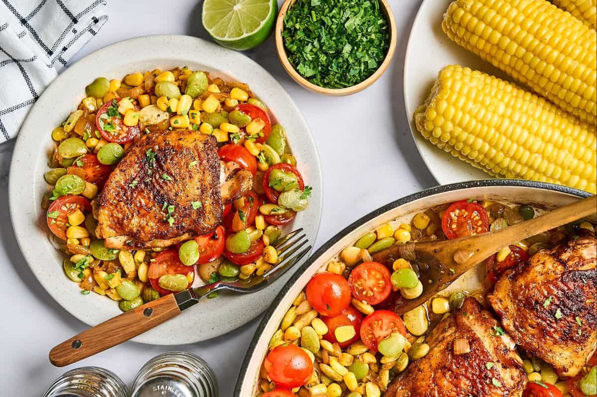 A plate of chicken succotash beside a skillet of more chicken succotash and other ingredients.