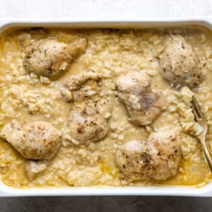 Chicken thighs in a creamy rice mixture, in a baking dish.
