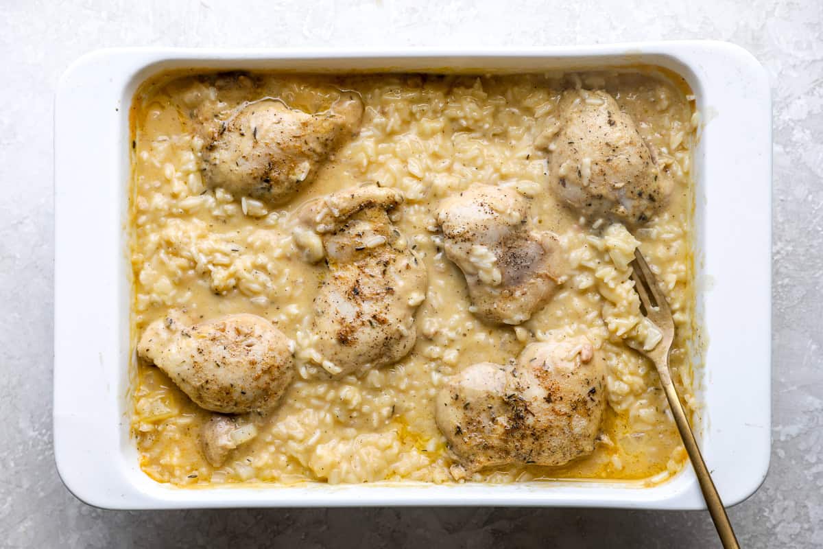 Chicken thighs in a creamy rice mixture, in a baking dish.