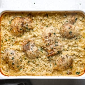 Baked chicken thighs in creamy rice casserole, garnished with parsley.
