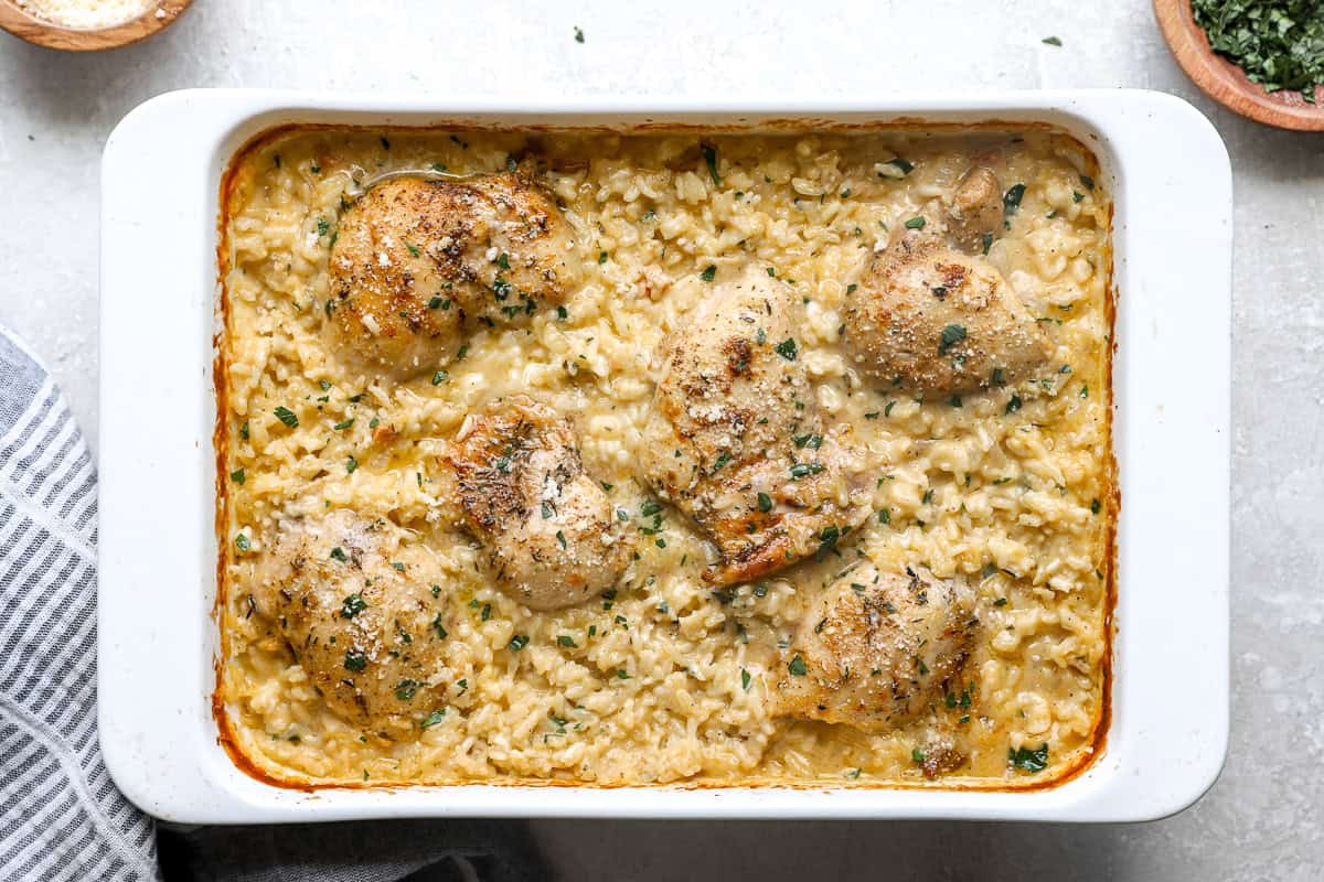 Baked chicken thighs in creamy rice casserole, garnished with parsley.
