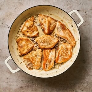 Seared chicken cutlets in a skillet over a creamy diane sauce.
