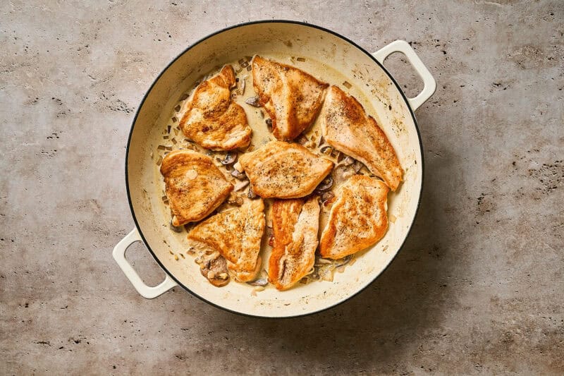 Seared chicken cutlets in a skillet over a creamy diane sauce.
