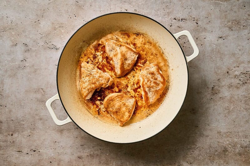 Seared chicken cutlets in a skillet.