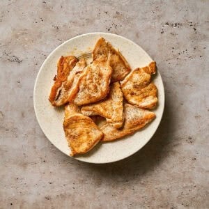 Cooked chicken cutlets on a white plate.